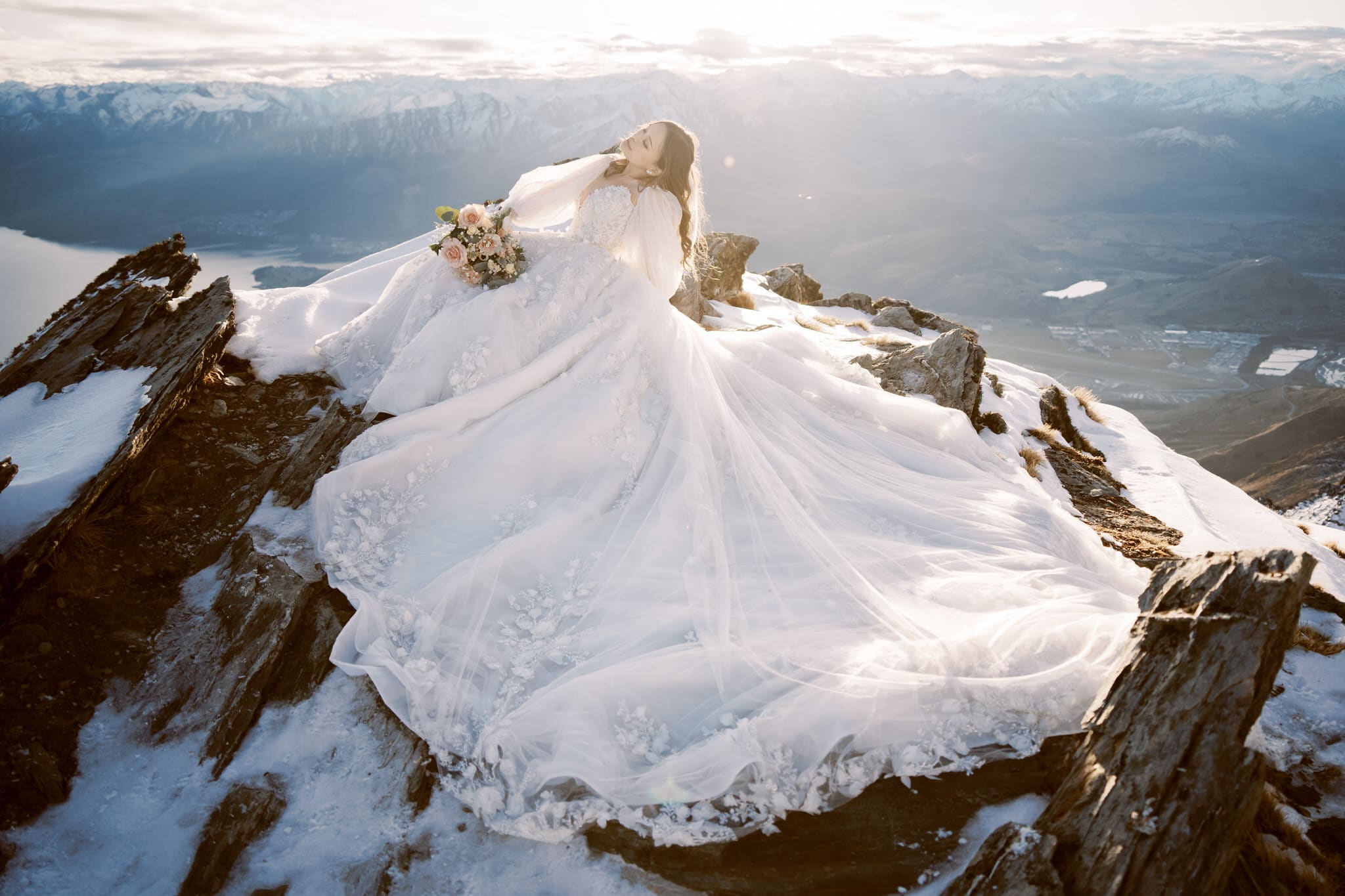 クイーンズタウン　ニュージーランド　ウェディング　前撮り　挙式　結婚式　フォトグラファー | 雪山の頂上に座るウェディングドレスを着たクイーンズタウンの花嫁。